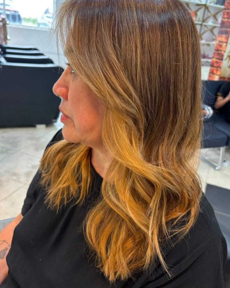 Cabelo castanho com pontas caramelo e ondas suaves, de perfil