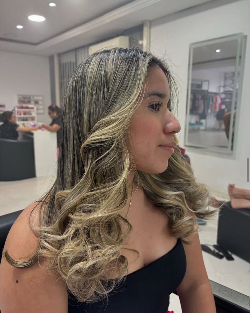 Cabelo com mechas loiras e cachos soltos, de perfil